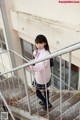 A young woman in a school uniform is standing on the stairs.